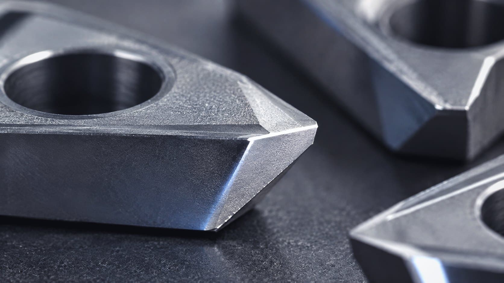 Close up of ground carbide cutting inserts on a dark surface